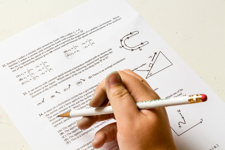 kartka papieru z zadaniami testowymi, widoczna ręka z ołówkiem