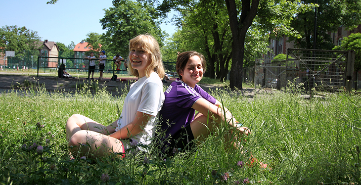 Dwie uśmiechnięte dziewczyny siedzą w trawie