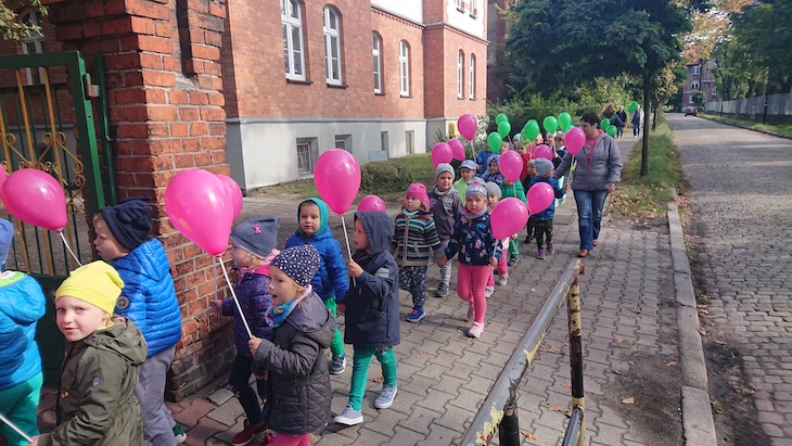 dzieci idą trzymając kolorowe balony