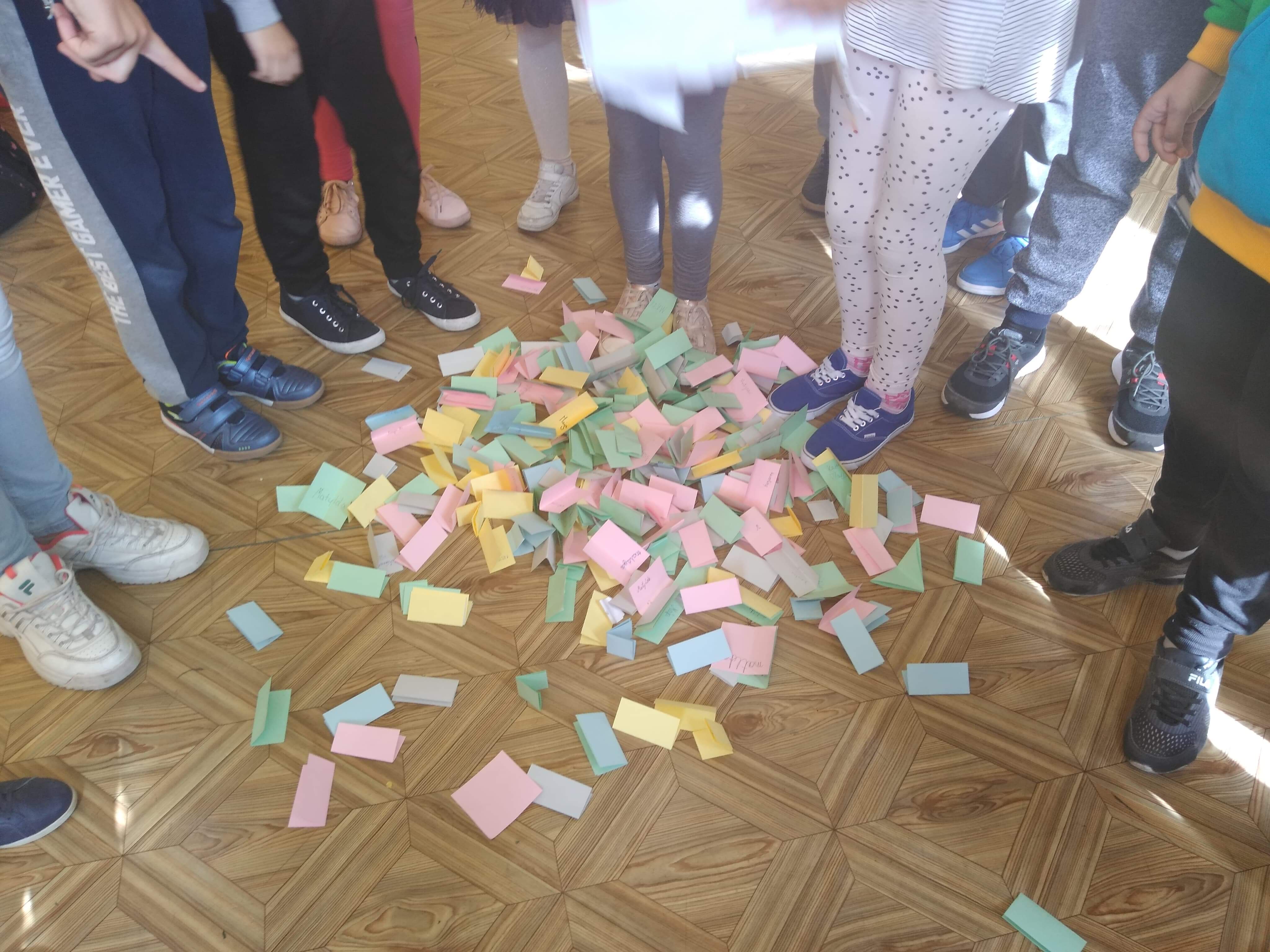Dzieci stoją a na podłodze wysypane są kraty do głosowania na samorząd uczniowski