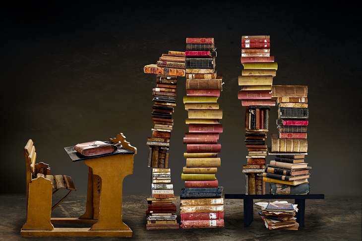 stara ławka szkolna, na której znajdują się stosy książek