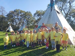 Dzieci ubrane w stroje indiańskie stoją przy dużych namiotach