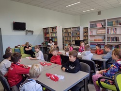 zajęcia konkursowe w bibliotece szkolnej z okazji święta niepodległości, uczniowie siedzą przy stołach