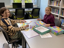 Dwie dziewczynki w bibliotece szkolnej  grają w grę planszową  gry planszowe, impreza zorganizowana z okazji  światowego dnia planszówek