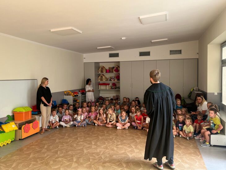 Na zdjęciu widzimy grupę starszaków słuchających opowiadania oraz ich nauczycielki