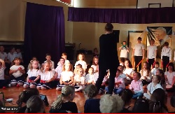 Uczniowie śpiewają dyrygowani przez nauczycielkę