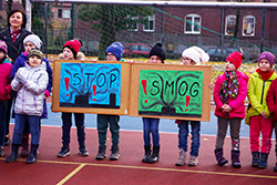 Uczniowie w kurtkach prezentują plakaty