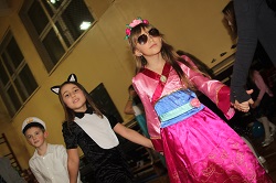 Dzieci tańczą w czasie Zabawy Karnawałowej. Na pierwszym planie dziewczynka w różowej sukience i dziewczynka przebraniu kota