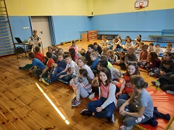 Uczniowie siedzą na podłodze i słuchają prelekcji "Bieg po zdrowie"