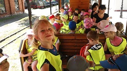 Dzieci w wagonie zabytkowej kolejki. Uśmiechnięta dziewczynka.