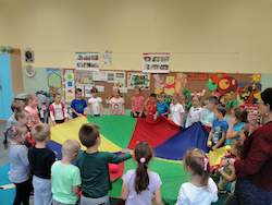 dzieci tańczą w kole z kolorową chustą