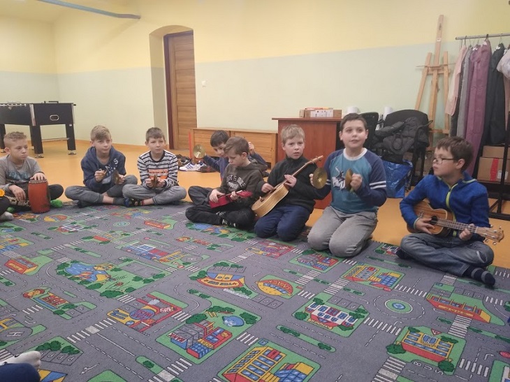 Dzieci siedzą na dywanie z gitarami