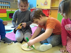 Dzieci odciskają figurki dinozaurów w masie solnej