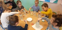 dzieci eksperymentują przy stolikach