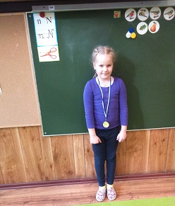 dziewczynka stoi ze złotym medalem