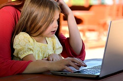 Dziecko siedzi przy komputerze z rodzicem
