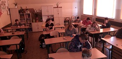 uczniowie siedzą w ławkach w sali lekcyjnej