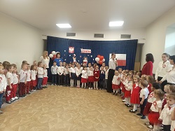 Dzieci odświętnie ubrane śpiewają hymn Polski. Sala udekorowana jest w symbole narodowe