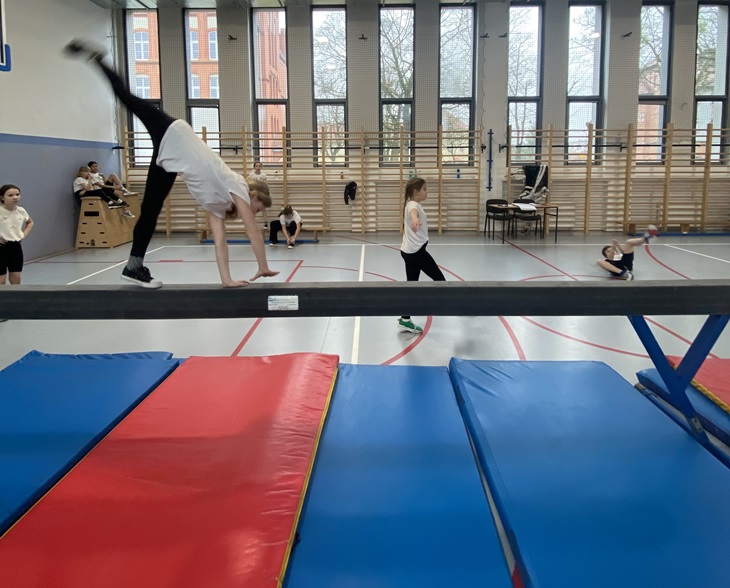 Dziewczynka ćwiczy na równoważni w sali gimnastyczne SP18