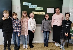 Uczestnicy szkolnego konkursu recytatorskiego z językia angielskiego i niemieckiego, dzieci stoją przy tablicy, pozują
