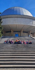 na zdjęciu grupa dzieci siedzi na schodach prowadzących do budynku Planetarium w Chorzowie 