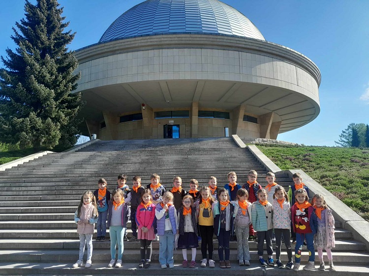 na zdjęciu grupa dzieci stoi na schodach prowadzących do budynku Planetarium w Chorzowie 