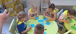 na zdjęciu dzieci siedzą przy stole i rysują konstelacje na kolorowych kartkach