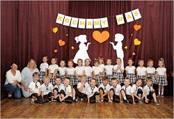 na Zdjęciu duża grupa dzieci ustawiona w dwóch rzędach, pozuje na tle  dekoracji z napisem Kochamy Was