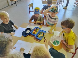 na zdjęciu grupa dzieci siedzi przy stoliku, przy którym odbywają się warsztaty
