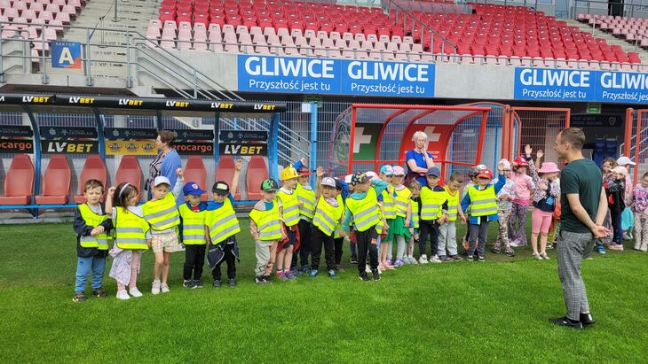 Dzieci na boisku Piasta Gliwice słuchają historii powstania klubu