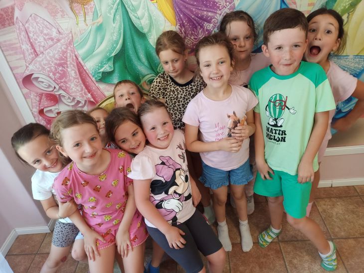 Grupka uśmiechniętych i zadowolonych dzieci na tle namalowanych na ścianie księżniczek