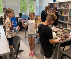 Uczniowie w bibliotece trzymają książki, obchody dni książki w szkole