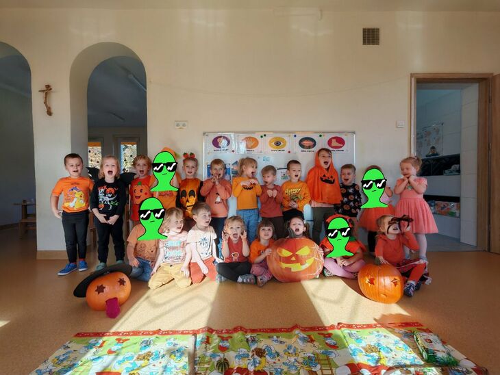 dzieci przebrane w barwach pomarańczowych a dookoła przystrojone dynie