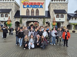 Na zdjęciu znajduje się grupa uczniów pozujących przed wejściem do Parku Rozrywki Energylandia w Zatorze. W tle widać charakterystyczną bramę z dużym napisem ENERGYLANDIA oraz dekoracje w bajkowym stylu. Uczniowie są ciepło ubrani, co wskazuje, że wycieczka odbyła się w chłodniejszy dzień.