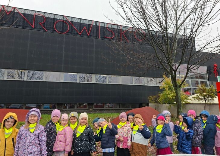 grupa uśmiechniętych dzieci ubranych w kurtki, stojące pod budynkiem - napis mrowisko