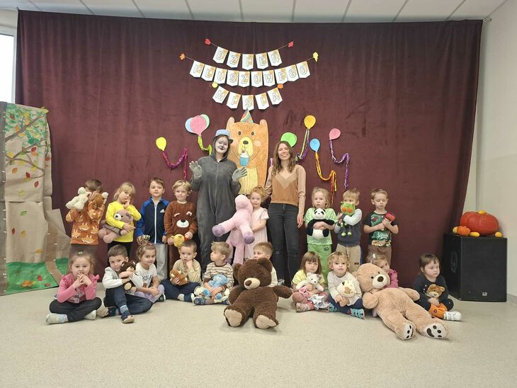 grupa dzieci siedząca z pluszowymi misiami, z wychowawczynią oraz postacią misia