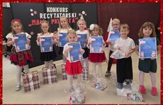 grafika przedstawia przedstawiający dzieci elegancko ubrane w barwy bialo czerwone, z dyplomami oraz upominkami