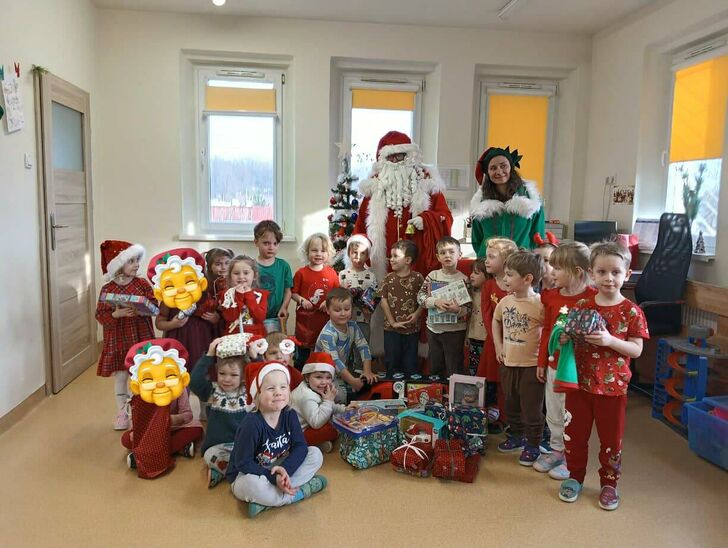 grupa uśmiechniętych dzieci z mikołajem oraz pomocnicą elficą