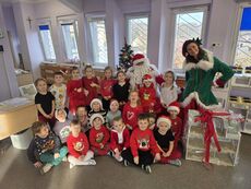 grupa uśmiechniętych dzieci z mikołajem oraz pomocnicą elficą