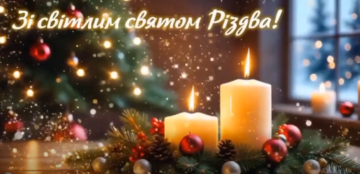 Na zdjęciu widać nastrojową, świąteczną scenę bożonarodzeniową. Na pierwszym planie stoją trzy zapalone świece ustawione na stroiku z gałązek iglastych, ozdobionym czerwonymi bombkami i szyszkami. Ciepłe światło świec tworzy przytulną, spokojną atmosferę.  W tle znajduje się choinka udekorowana światełkami, a za nią okno, przez które widać zimowy krajobraz i delikatnie padający śnieg. Całość utrzymana jest w ciepłych, złotych barwach, podkreślających magię Świąt.  W górnej części obrazu widnieje napis w języku ukraińskim: „Зі світлим святом Різдва!”, co oznacza: „Z jasnym świętem Bożego Narodzenia!”.