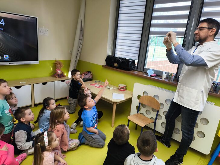 lekarz dentysta pokazuję dzieciom model szczęki oraz prezentuje jak prawidłowo myć zęby