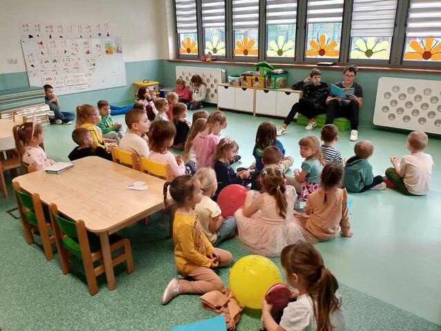 dzieci siedzące w kole na podłodze 