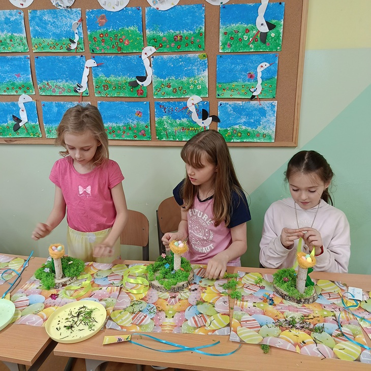 dziewczynki trzy przy stole dekorują ozdoby wielkanocne