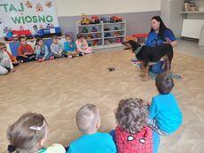 pies z terapeutą w otoczeniu siedzących na podłodze dzieci