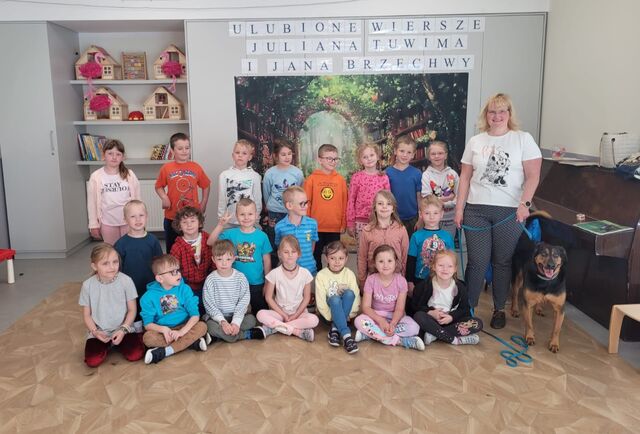 grupa uśmiechniętych dzieci stojąca obok psa