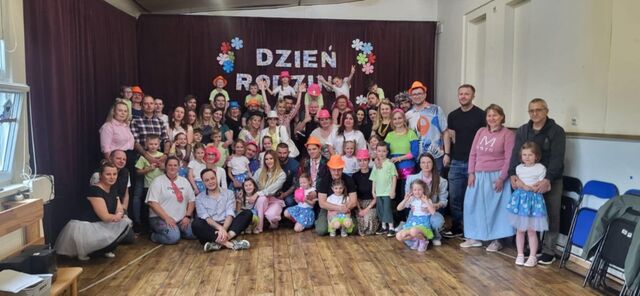 grupa uśmiechniętych dzieci i rodziców pod sceną, na występie ubrani w stroje