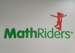 Na zdjęciu znajduje się logo MathRiders — programu edukacyjnego z zakresu matematyki. Logo przedstawia zielony napis „MathRiders®”