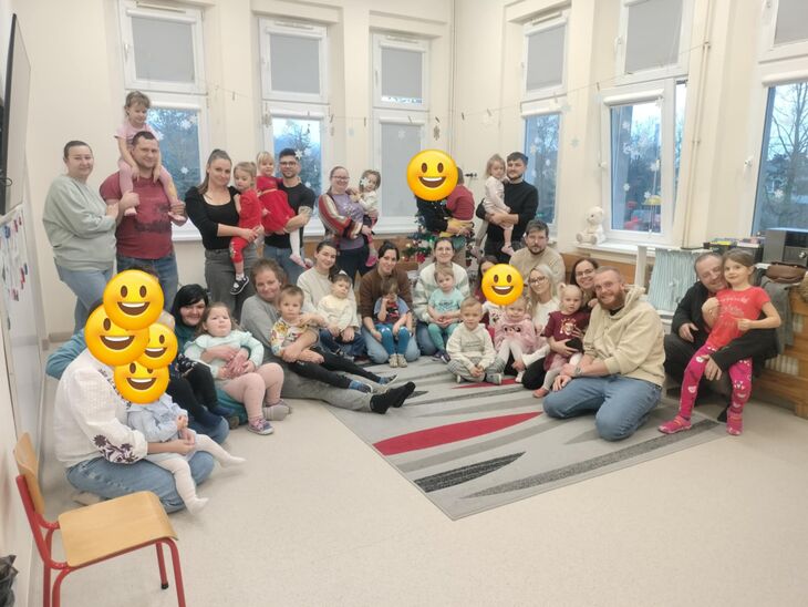 grupa rodziców z dziećmi siedząca w sali, uczestnicząca w warsztatach zorganizowanych na terenie przedszkola