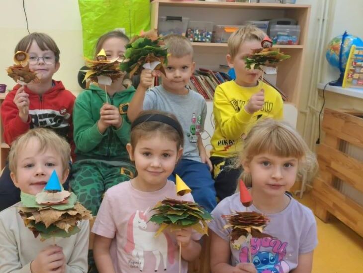 uśmiechnięte dzieci z kasztankami i liśćmi