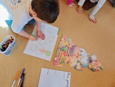 chłopiec pochylający się nad kartą pracy i kreślący po śladzie